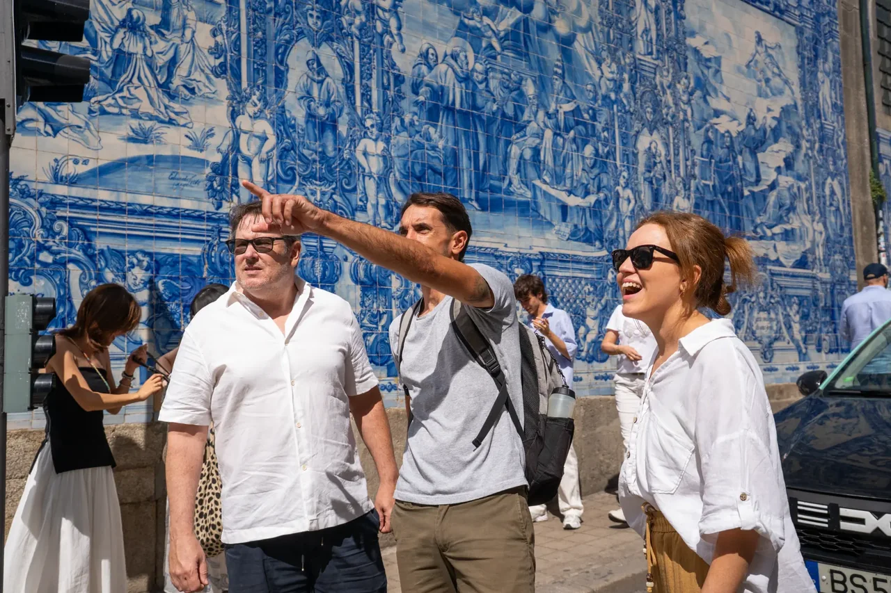 Thiago Costa guiding a couple beside the blue-tiled Capela das Almas in Porto.
